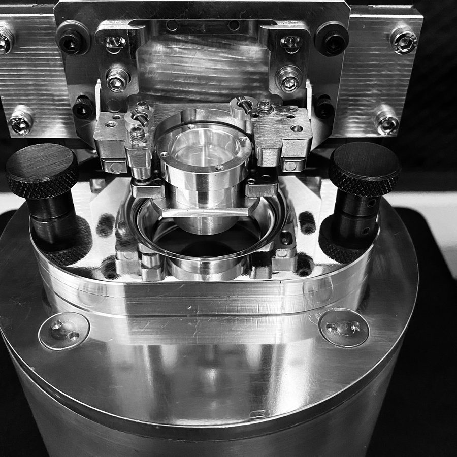 A precision clamping fixture holding a small cylindrical part under a press