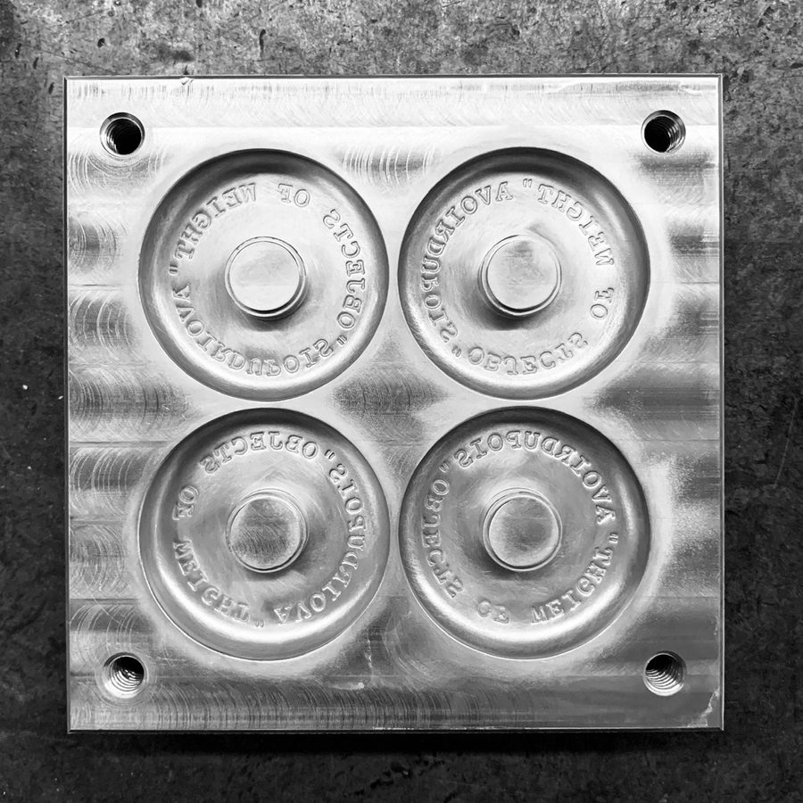 A square aluminum mold plate with four recessed, mirror-engraved discs