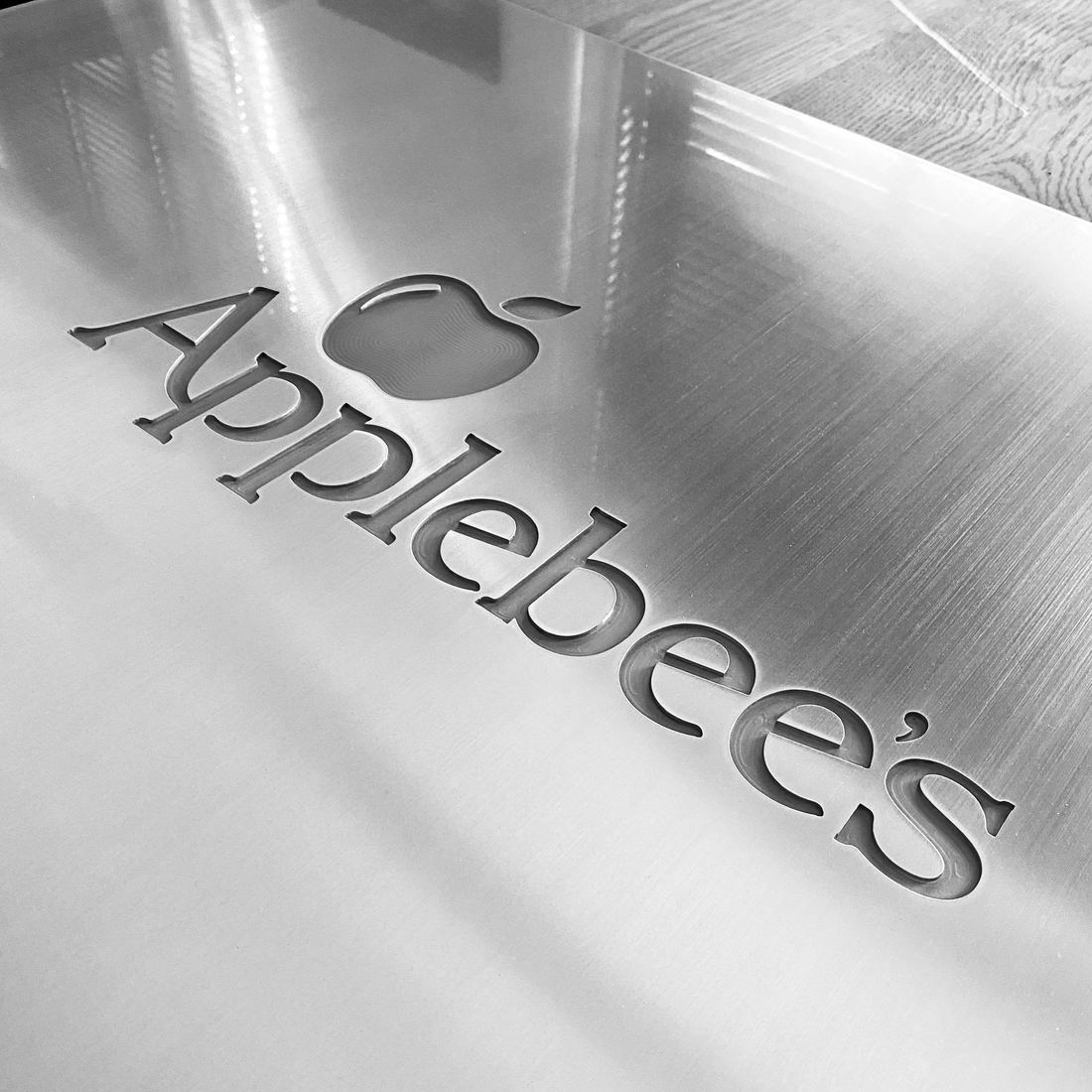 A company name and apple logo machined into a brushed aluminum plate