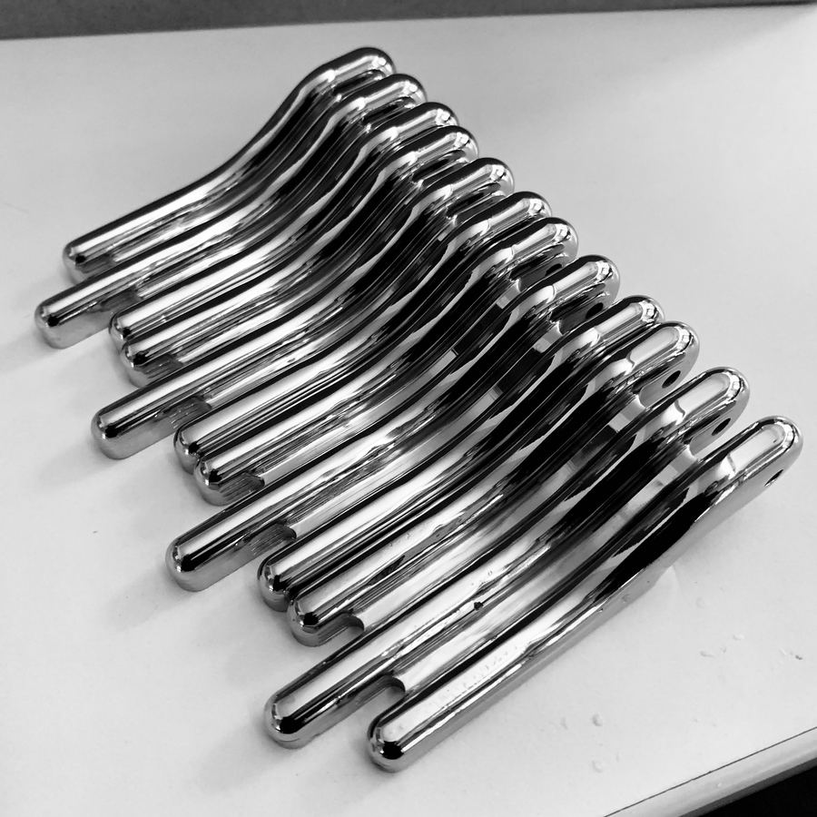 A stack of polished curved brass hinges laid on a work surface