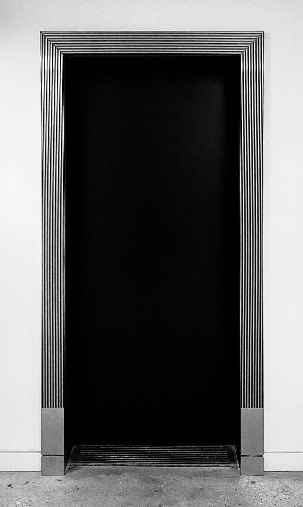 Fluted elevator trim with mitered corners, set in a white wall