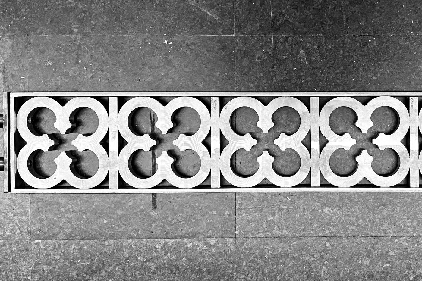 A circa-1910 ventilation shaft grating recreation in iron, a row of four-lobed openings set in a frame